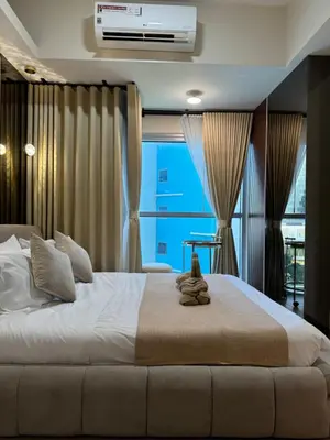 a bedroom with a large white bed and a window at Stylish 1BR Near Airport Facing the Bay - 7b in Manila