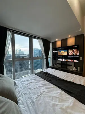 a bedroom with a large bed and a large window at Staycations Up Above 17 at BGC in Manila