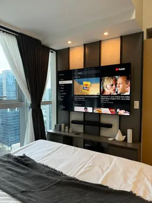 a bedroom with a bed and a flat screen tv at Staycations Up Above 17 at BGC in Manila