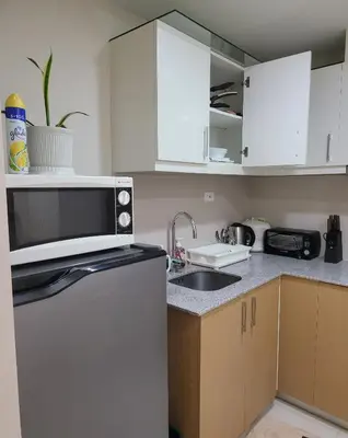a kitchen with a sink and a microwave at Staycations Up Above 13 at BGC in Manila