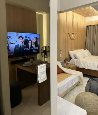 a hotel room with a bed and a flat screen tv at One Uptown Residences at BGC - Staycations Up Above 15 in Manila
