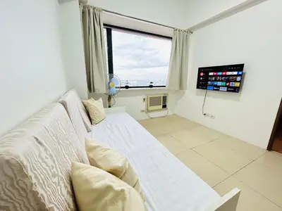 a living room with a couch and a large window at Budget Family Room at Ace Suites by the Famous Indoor Water Spa in Manila