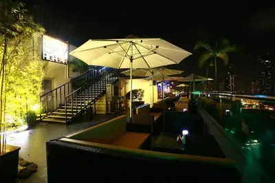 a restaurant with an umbrella and a pool at night at Budget Family Room at Ace Suites by the Famous Indoor Water Spa in Manila