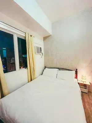 a white bed in a room with a window at Condo unit in Manda near Edsa, Shangrila, Megamall in Manila
