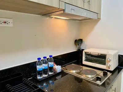 a kitchen with bottles of water and a microwave at Casa Eleganza at Fame Residences - 1BR corner unit, CBD, Gym, Pool, WiFi, Great View in Manila