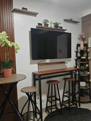a desk with stools and a television on a wall at Zeki's Place - Shore 2 Residences MOA in Manila