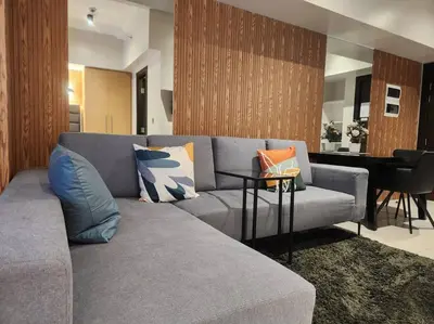a living room with a gray couch and a table at BGC Cosy Hotel Vibe Uptown Parksuites Studio in Manila