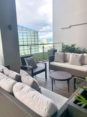 a living room with couches and chairs on a balcony at BGC Cosy Hotel Vibe Uptown Parksuites Studio in Manila