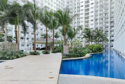 a resort swimming pool with palm trees and buildings at Lascianos SMDC Shore Residences by RedDoorz in Manila