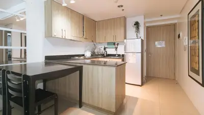 a kitchen with wooden cabinets and a white refrigerator at Lascianos SMDC Shore Residences by RedDoorz in Manila