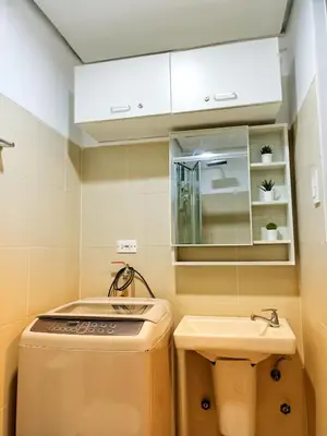 a small bathroom with a sink and a washer at Fame Residence Tower 1 Cozy Hotel Style 1 Bedroom with Balcony pool View in Manila