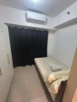 a small room with a bed and a air conditioner at Oasis MOA- Sea Residences in Manila