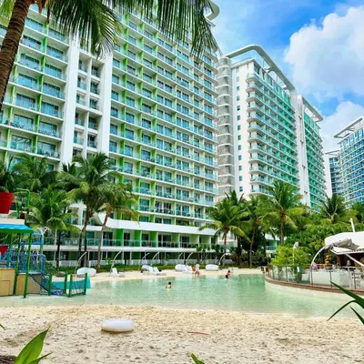 a swimming pool in front of a large building at 2 Bedroom Summer Themed Unit at Azure in Manila