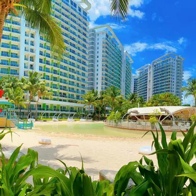 a beach in front of a resort with tall buildings at 2 Bedroom Summer Themed Unit at Azure in Manila