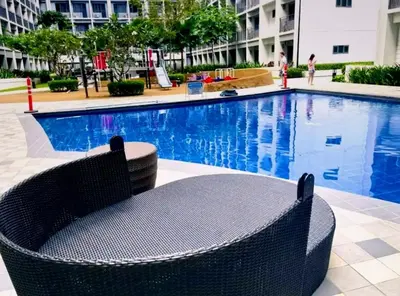 a swimming pool with a wicker chair next to a building at Hotel-Like Staycation2 MOA Pasay in Manila
