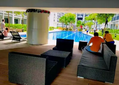 a group of people sitting on chairs near a swimming pool at Hotel-Like Staycation2 MOA Pasay in Manila