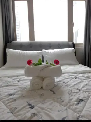 a white bed with two red flowers on it at Luxury Bayview Condo MOA & PICC Free WiFi in Manila