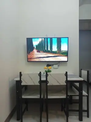 a tv on a wall with a table and two chairs at Luxury Bayview Condo MOA & PICC Free WiFi in Manila