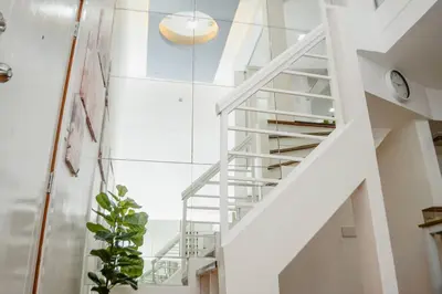 a white staircase in a room with a plant at Metro Stay - Prime Spot Near Malls & Major Cities in Manila