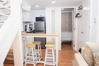 a kitchen with a counter and stools in a room at Metro Stay - Prime Spot Near Malls & Major Cities in Manila