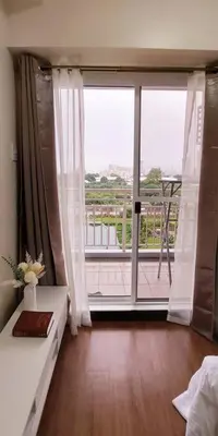 a bedroom with a large window with a view of a balcony at Helaena's Scandi Haven in Manila