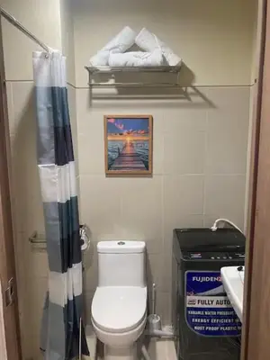 a bathroom with a toilet and a shower curtain at Comfortable and Cozy 1BR unit near MOA in Manila