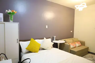 a bedroom with a bed with yellow pillows and a chair at Sojourner's Suite at 605, City-view condotel near the airport at Monte Carlo Residences Charlene in Manila