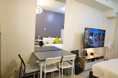 a room with a table and chairs and a bedroom at Sojourner's Suite at 605, City-view condotel near the airport at Monte Carlo Residences Charlene in Manila