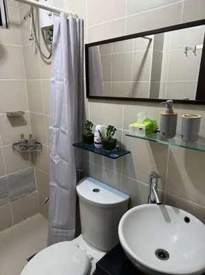 a bathroom with a toilet and a sink and a mirror at Ram's crib at san lorenzo's place condo in Manila