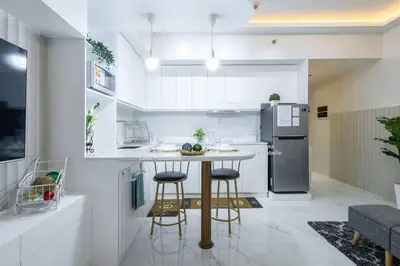 a kitchen with a table and two bar stools at Casa Feliza Belle-veranda overlooking Venice Grand Canal Gondola ride, with pool,gym,tennis,basketball courts,sauna and massage room in Manila