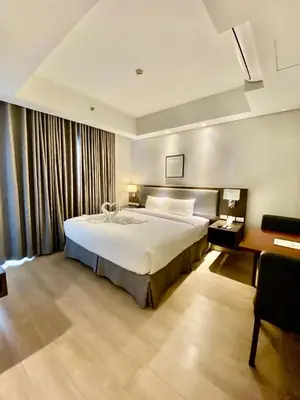 a bedroom with a large white bed and a desk at The Metro Nest at Bonifacio Civic Center Tower in Manila