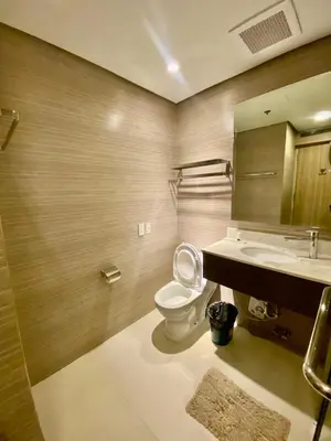 a bathroom with a toilet and a sink and a mirror at The Metro Nest at Bonifacio Civic Center Tower in Manila
