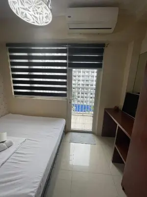 a bedroom with a bed and a window with blinds at Shore Residence Pool view Mall of Asia in Manila
