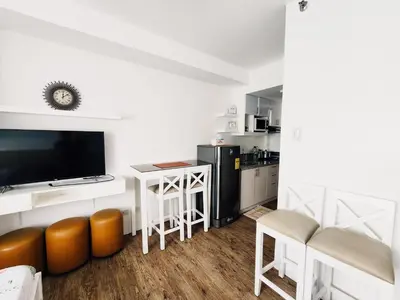 a living room with a kitchen with a tv and a table at Mannah's Place in Santo Domingo