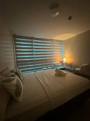 a bedroom with a large bed with a window at Cozi Uptown 1br suite Mitsukoshi Mall BGC in Manila