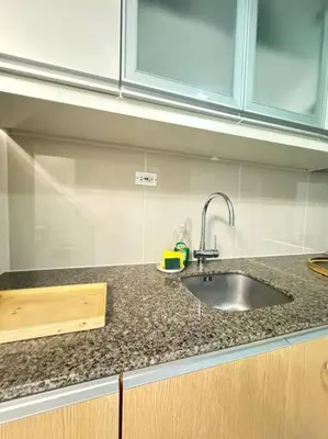 a kitchen with a sink and a counter top at Cozi Uptown 1br suite Mitsukoshi Mall BGC in Manila