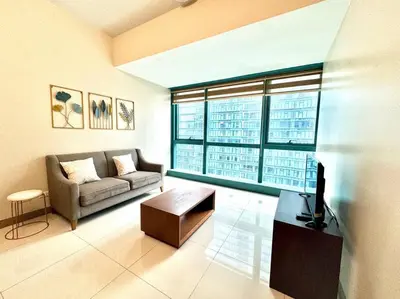 a living room with a couch and a large window at Cozi Uptown 1br suite Mitsukoshi Mall BGC in Manila