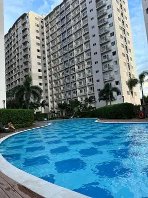 a large blue swimming pool in front of a building at Las Pinas City Cozy Escape in Manila