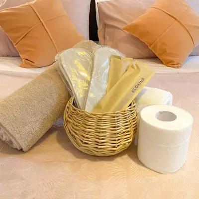 a basket of towels and a roll of toilet paper on a bed at Amethyst Suites Azure in Manila