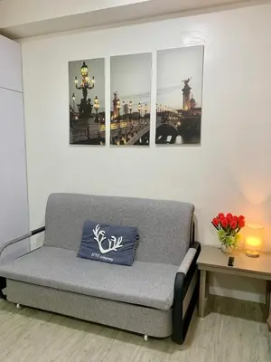 a couch in a living room with some pictures on the wall at Cozy Condominium at Amaia Steps Nuvali in Pitland