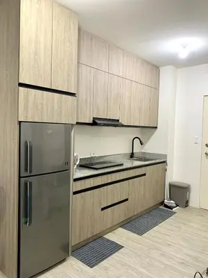 a kitchen with wooden cabinets and a stainless steel refrigerator at Cozy Condominium at Amaia Steps Nuvali in Pitland