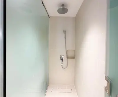 a shower in a bathroom with white walls at The Hotel at Tower Acqua 1 in Manila
