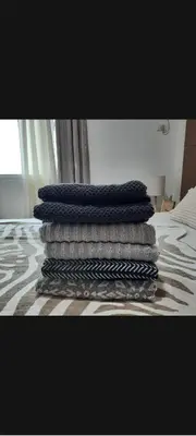 a pile of towels stacked on top of a bed at Quaint One Br Apartment in Manila