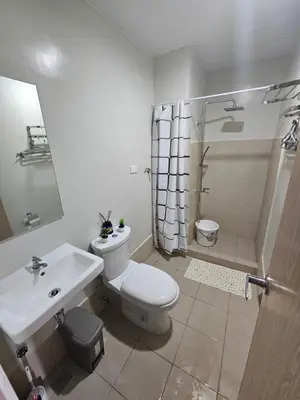 a bathroom with a toilet and a sink and a shower at DreamEscape by Charm Residences in Manila
