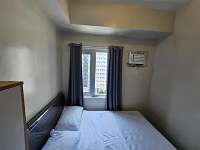 a small bedroom with a bed and a window at DreamEscape by Charm Residences in Manila