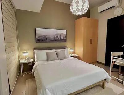 a bedroom with a large white bed and a chandelier at Uptown BGC in Manila