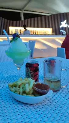 a table with a plate of food and a drink at Aesthetic Beach View Unit in Azure Parañaque in Manila