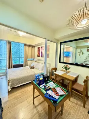 a bedroom with a bed and a desk with a table sidx sidx sidx at Aesthetic Beach View Unit in Azure Parañaque in Manila