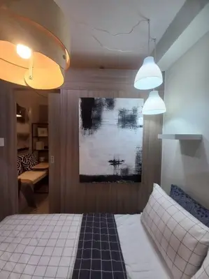 a bedroom with a bed and two pendant lights at Modern Rustic 1-Bed Condo in MoA Complex in Manila