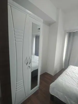 a white cabinet with a mirror in a bedroom at 1br at Air Makati Ayala near Makati med in Manila